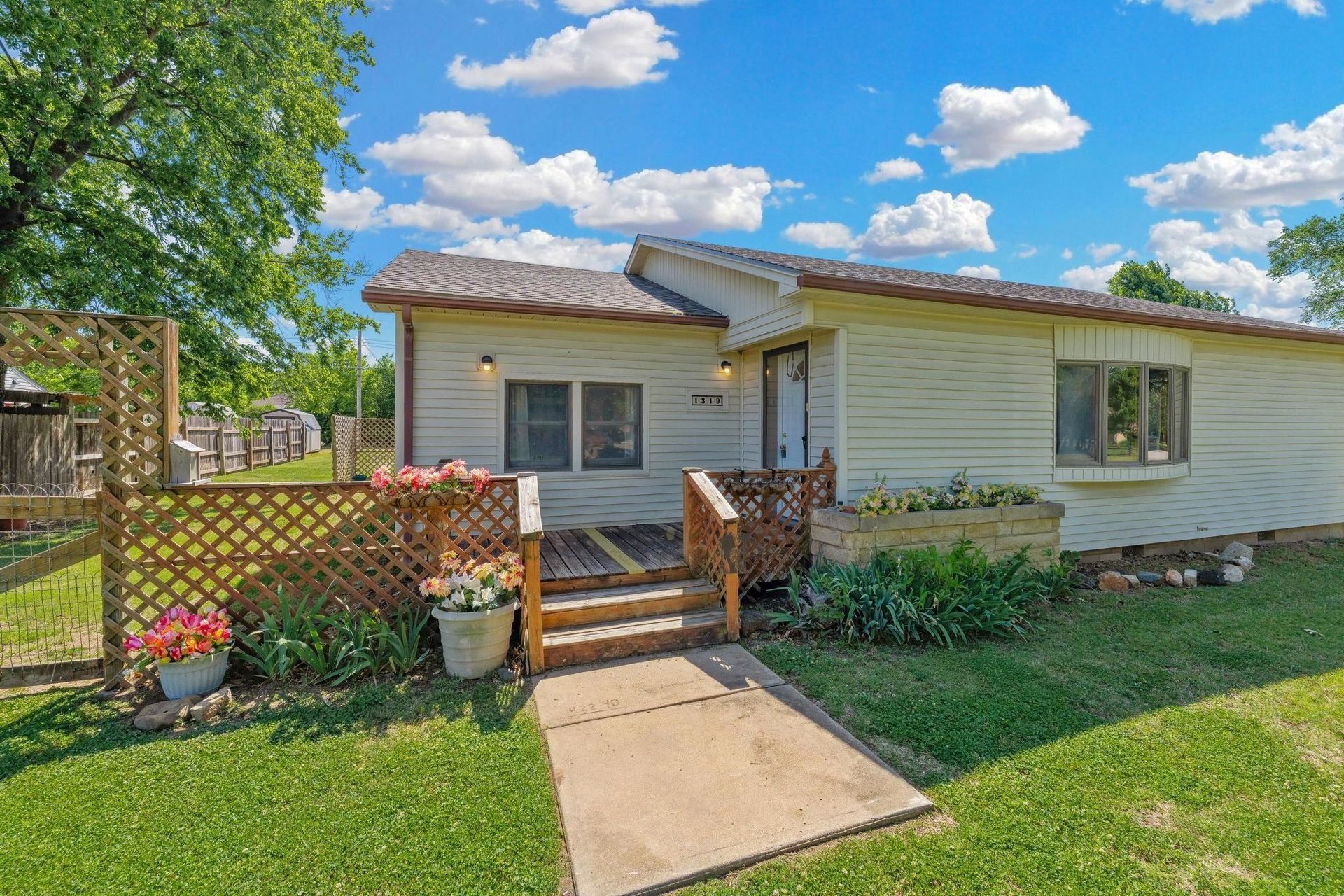 Single-story white house with a small front porch, walkway, and green yard under a blue sky
