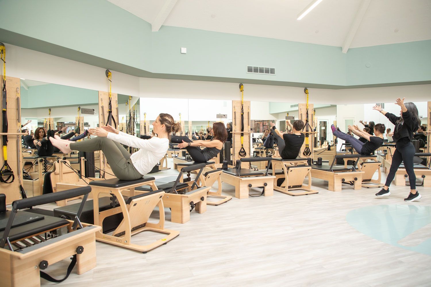 A group of people are doing pilates exercises in a gym.