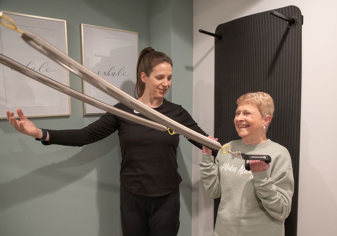 A woman is teaching another woman how to use a resistance band.