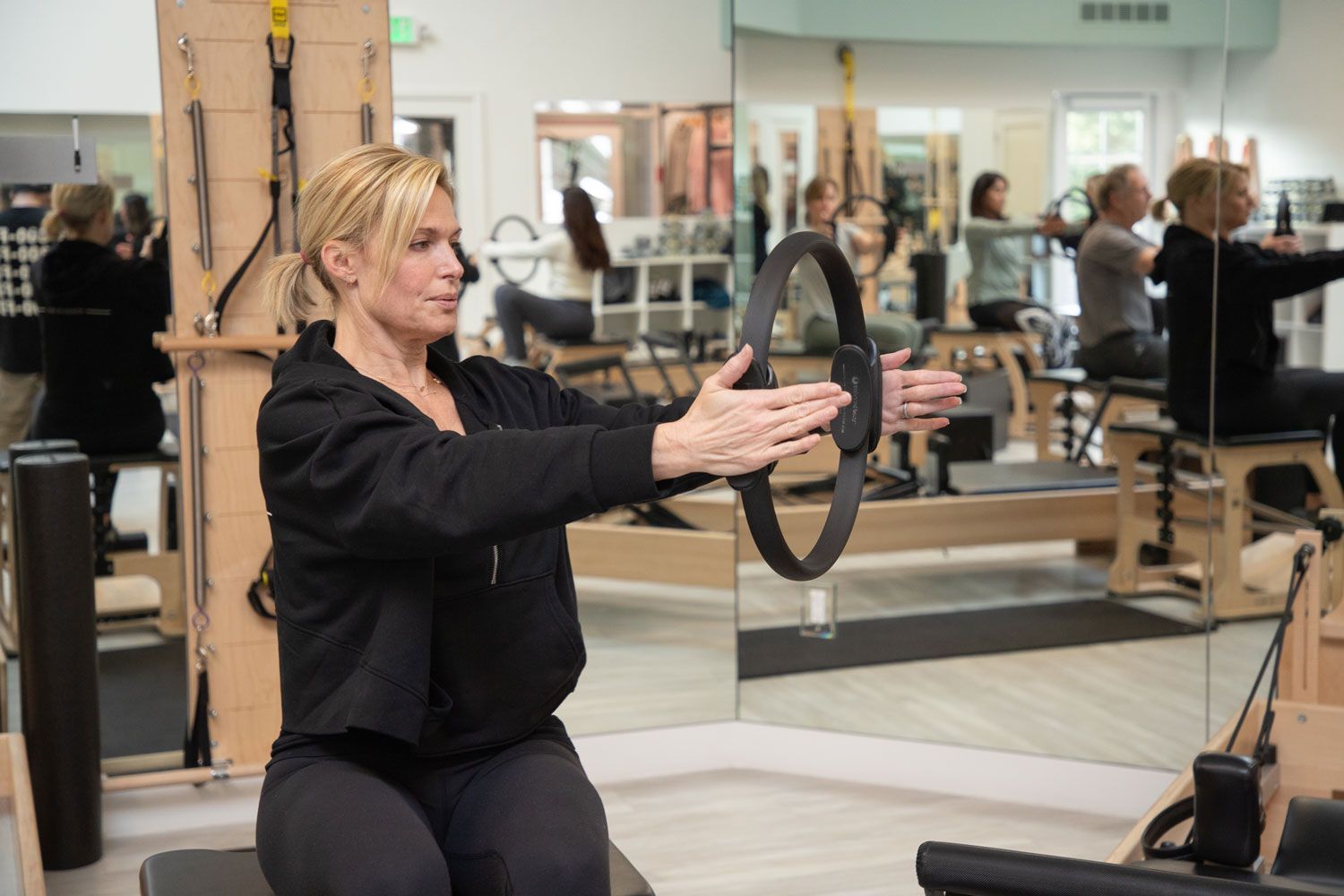 A woman is using a pilates ring in a gym.