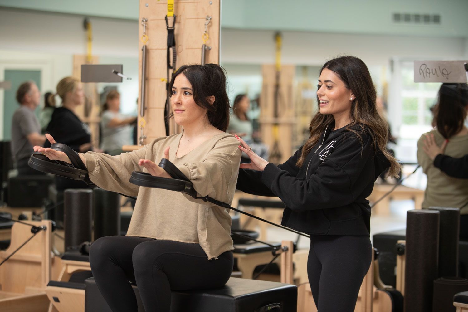 A woman is teaching another woman how to do pilates in a gym.
