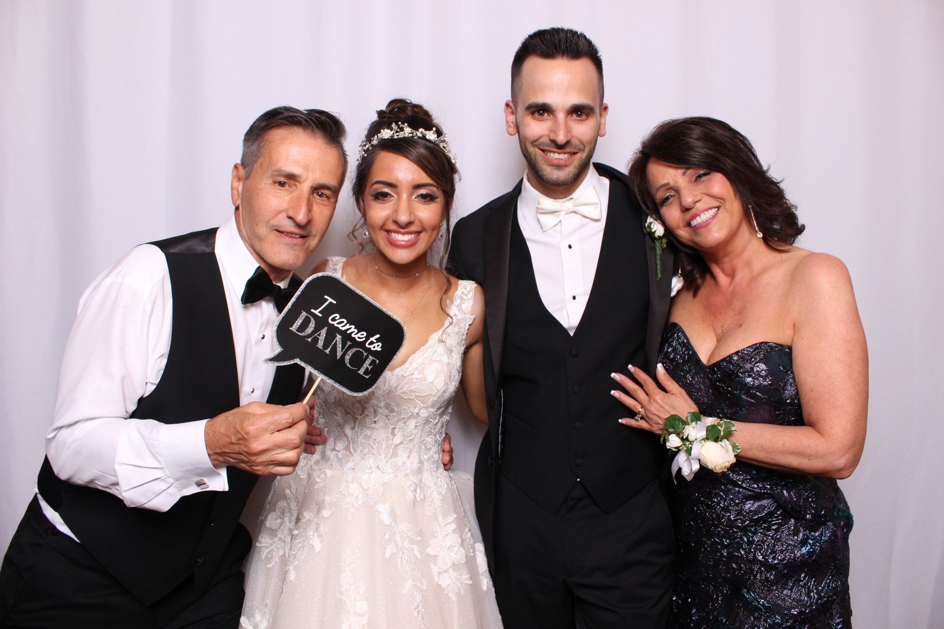 a bride and groom are posing for a picture with their parents in a photo booth.