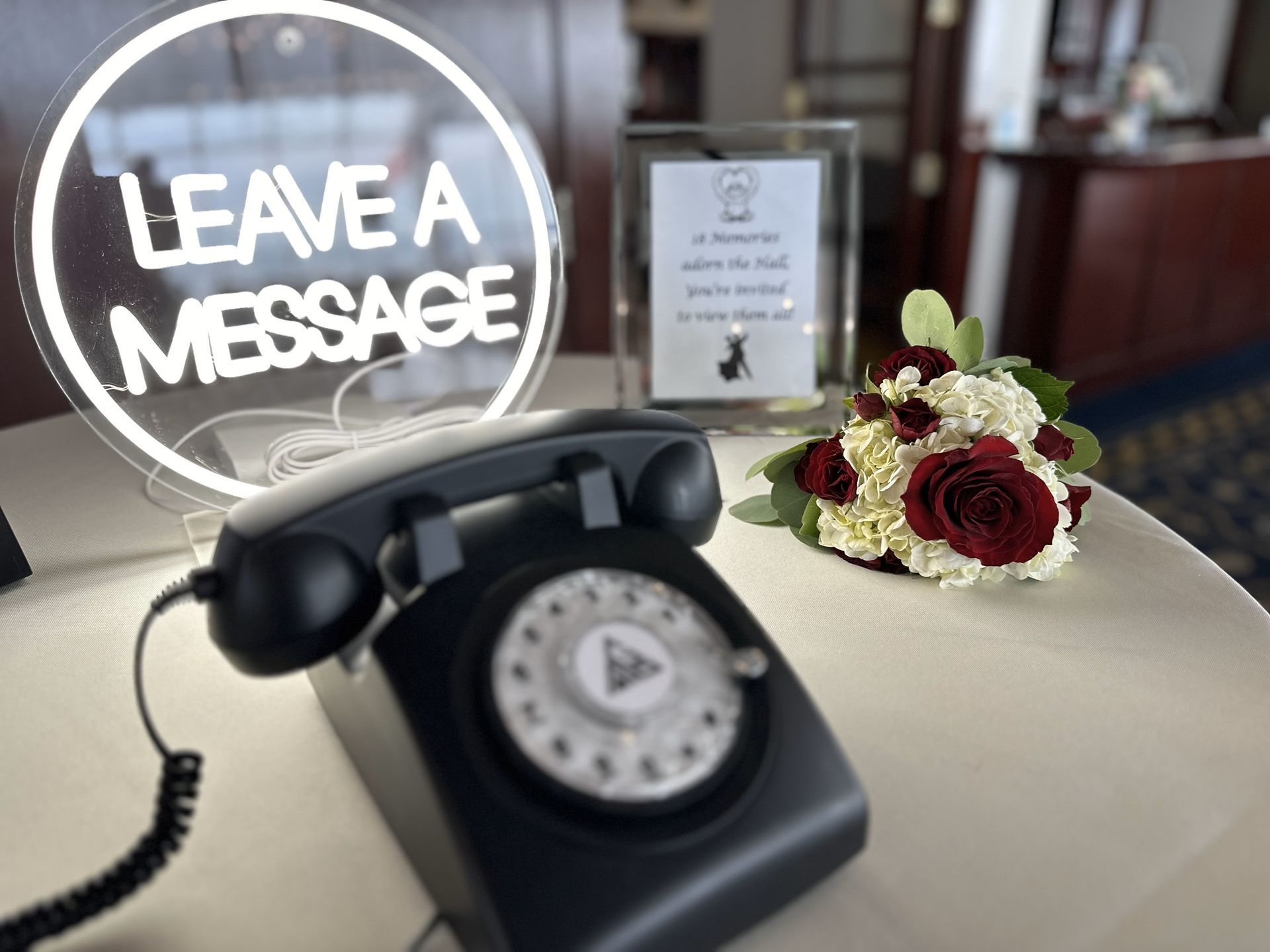 a black telephone is sitting on a table next to a sign that says leave a message .