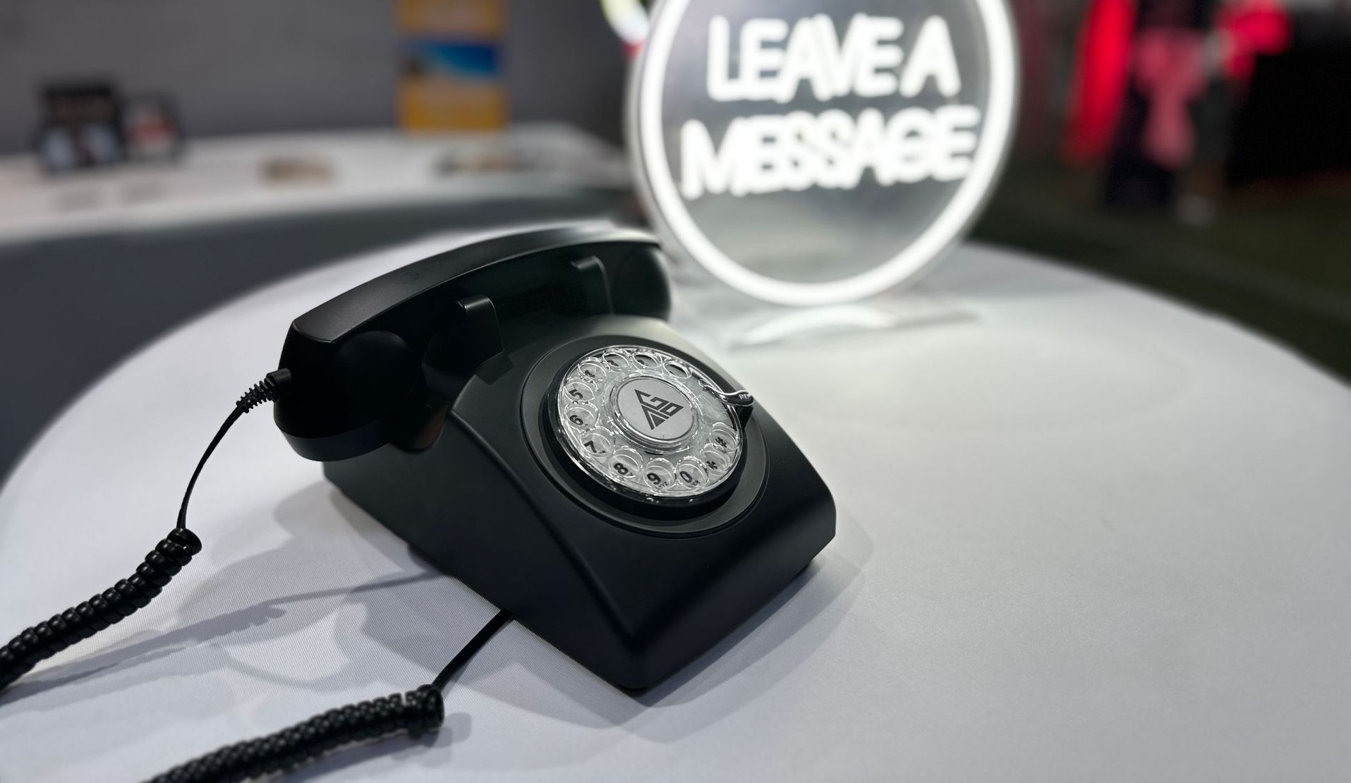 a black telephone is sitting on a white table next to a sign that says leave a message