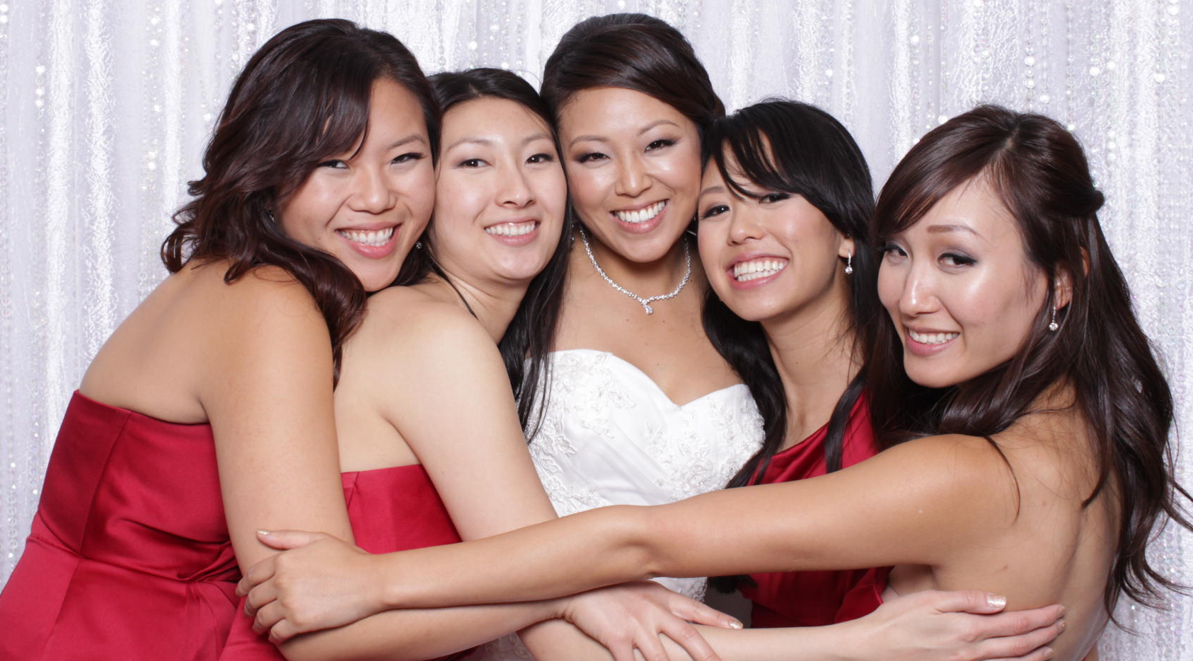 A bride and her bridesmaids are posing for a picture in a photo booth.