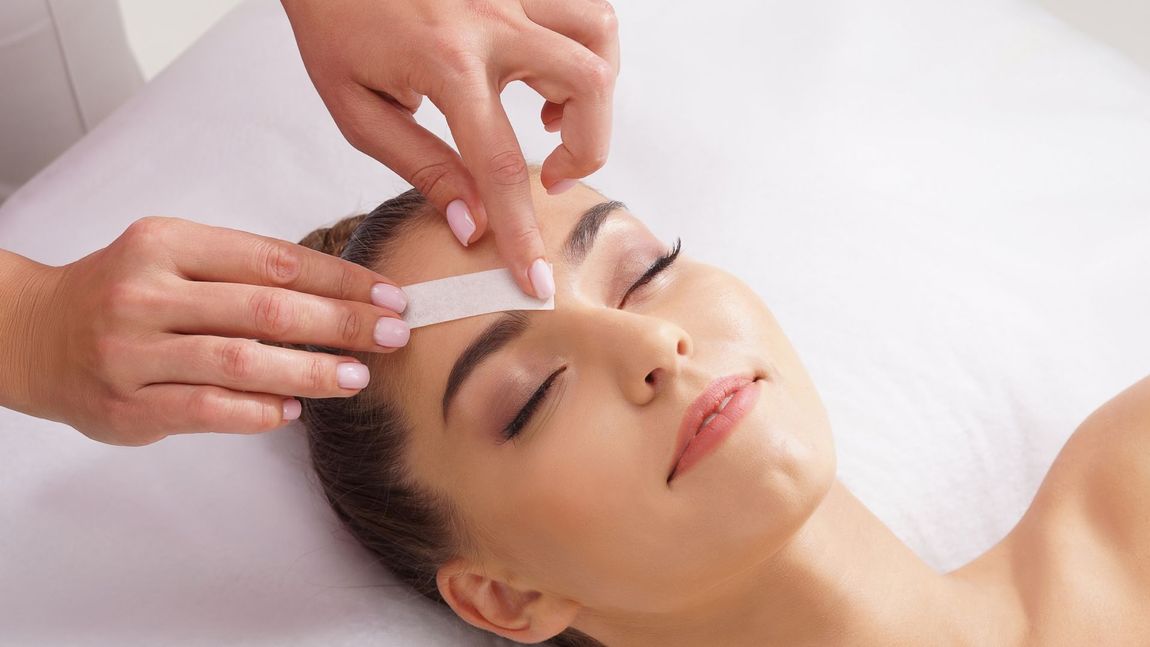 A woman is getting her eyebrows waxed in a beauty salon.