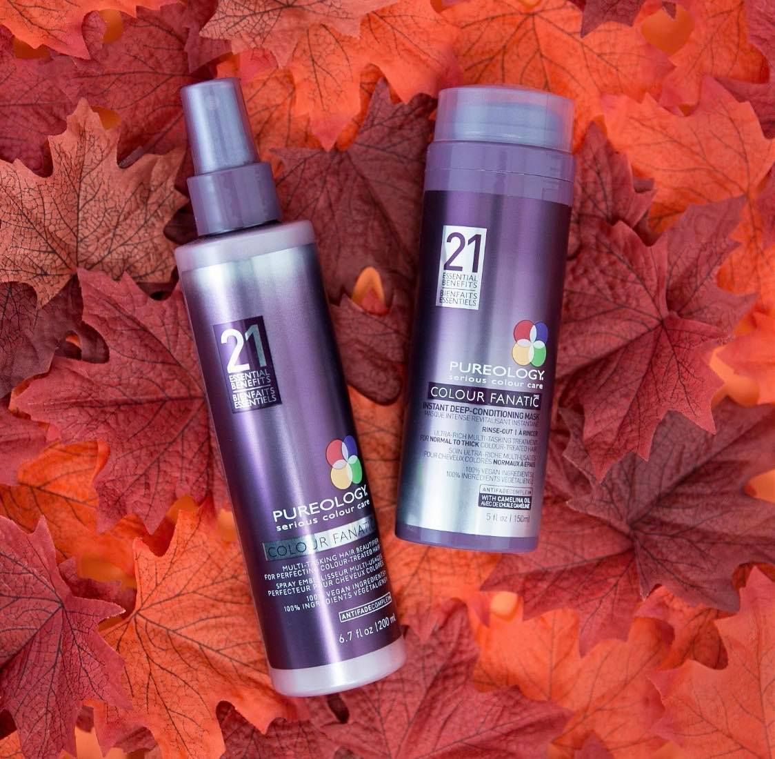 Two bottles of shampoo and conditioner are sitting on a pile of leaves.