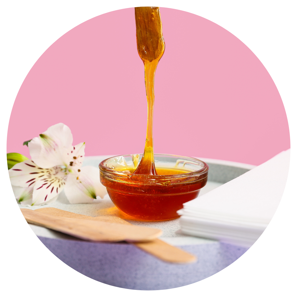 A bowl of honey is being poured into a wooden spoon.