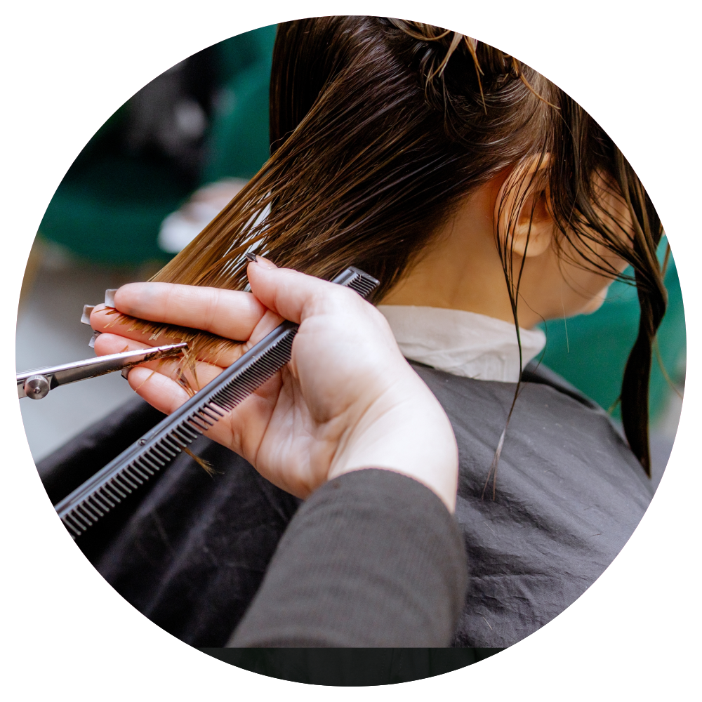 A woman is getting her hair cut by a hairdresser.