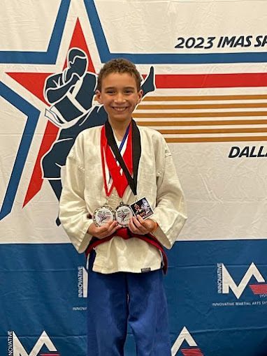 A young boy is standing on a podium holding a medal.