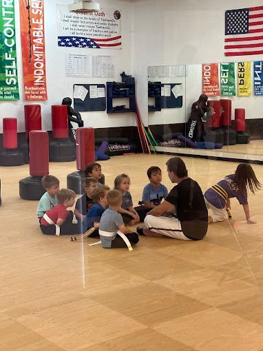 A group of children are sitting on the floor in a gym.