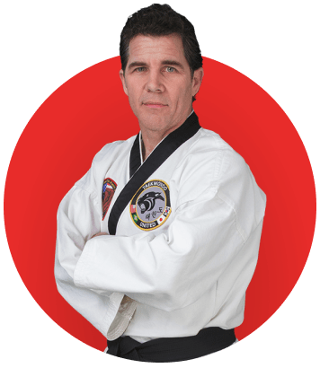 A man in a karate uniform is standing with his arms crossed