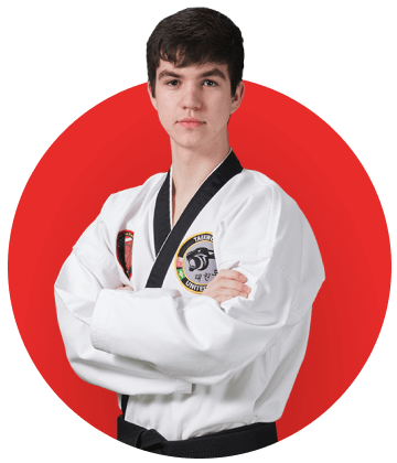 A young man in a taekwondo uniform is standing with his arms crossed in a red circle.