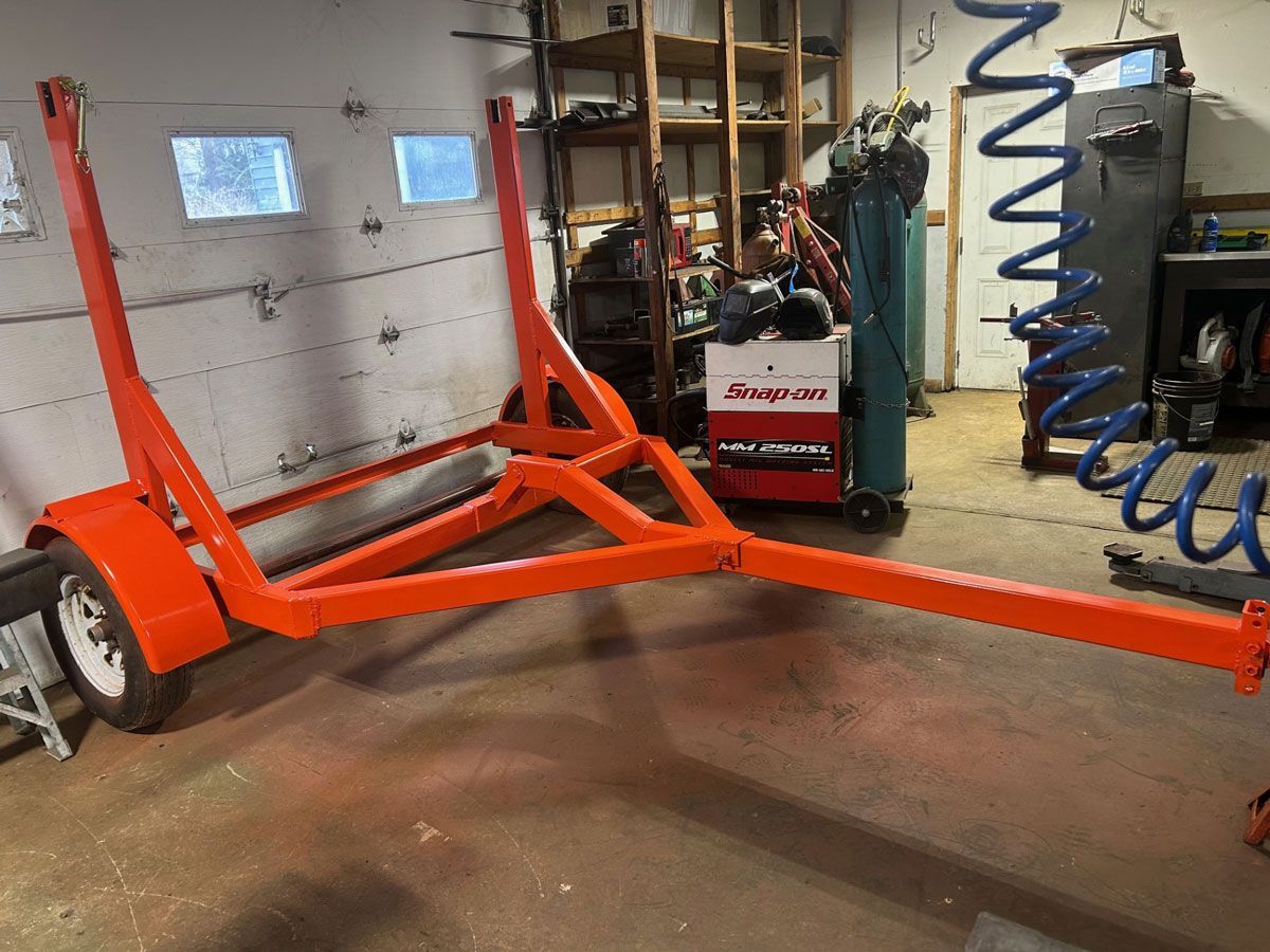 Orange trailer with white wheels in a workshop.