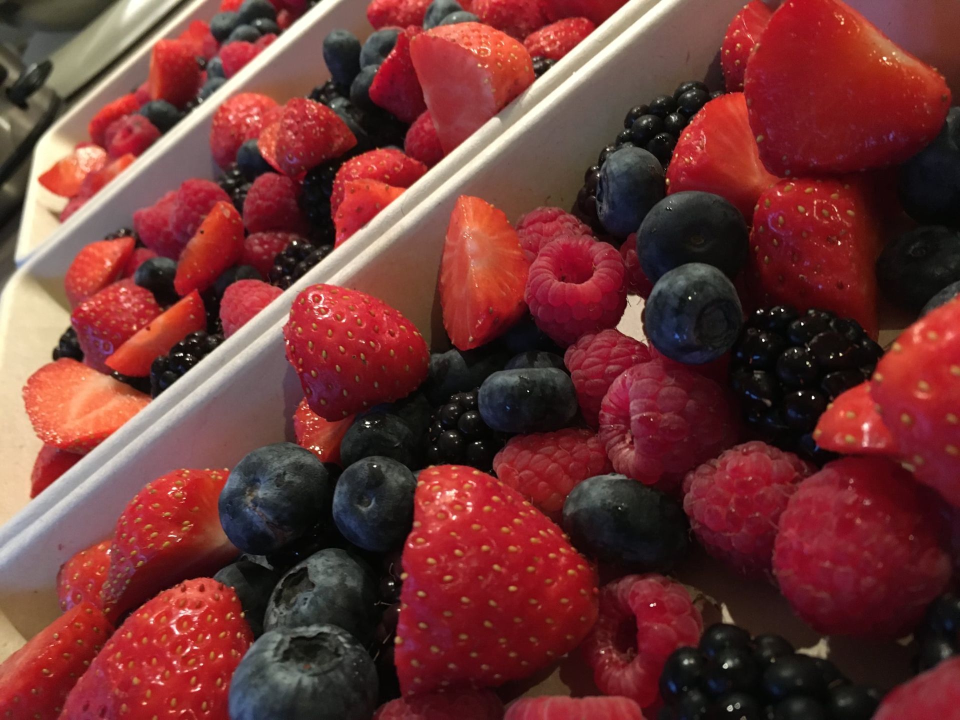 Aardbeien, frambozen, bosbessen en bramen in witte bakjes