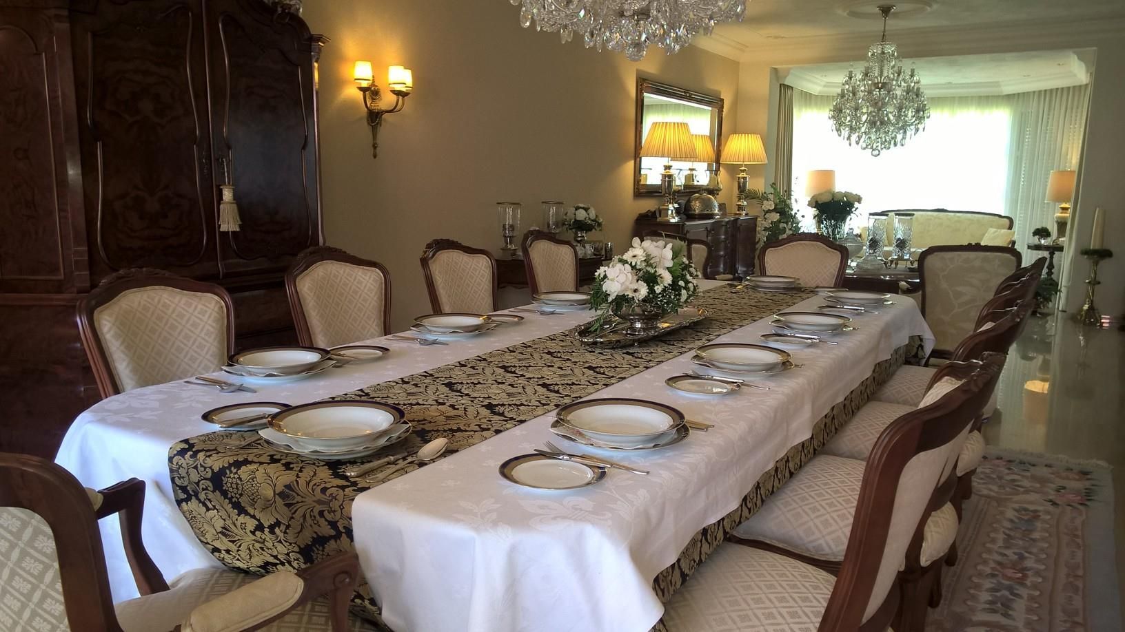 Een lange tafel met borden en bestek erop in een eetkamer