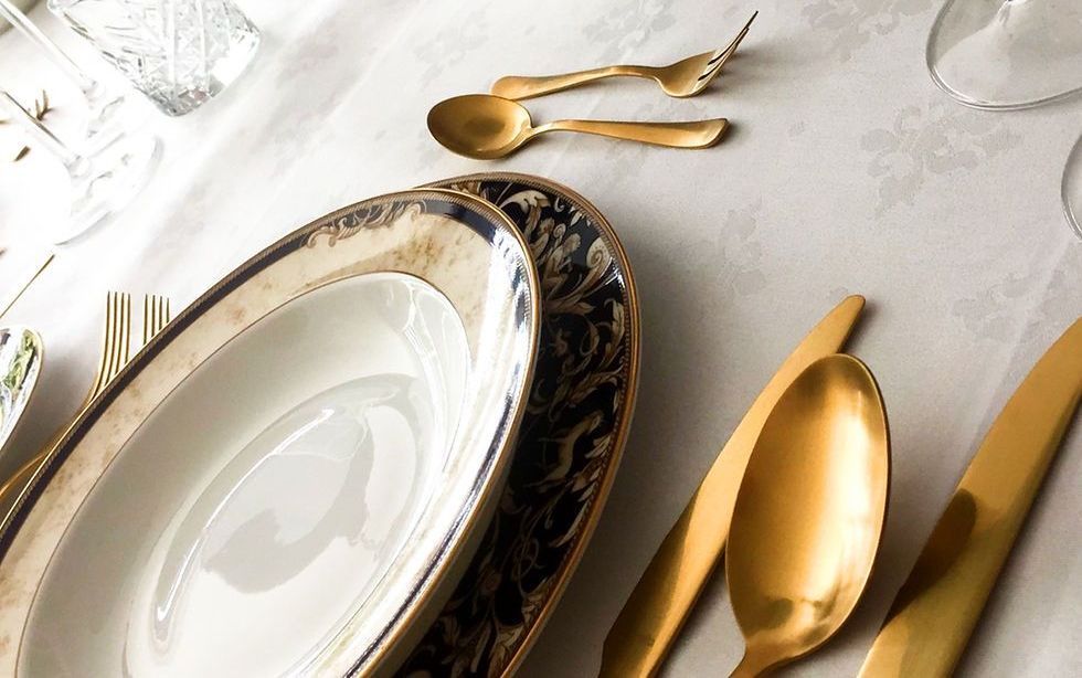 Een tafel met borden, lepels, vorken, messen en glazen erop.