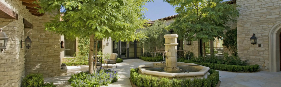 There is a fountain in the middle of the courtyard between two buildings.