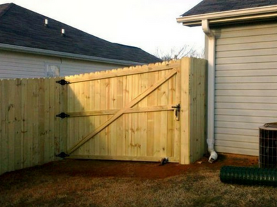 A wooden fence with a door in the backyard of a house