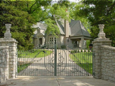 A large house is behind a wrought iron gate