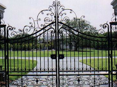 A wrought iron gate leading to a lush green field