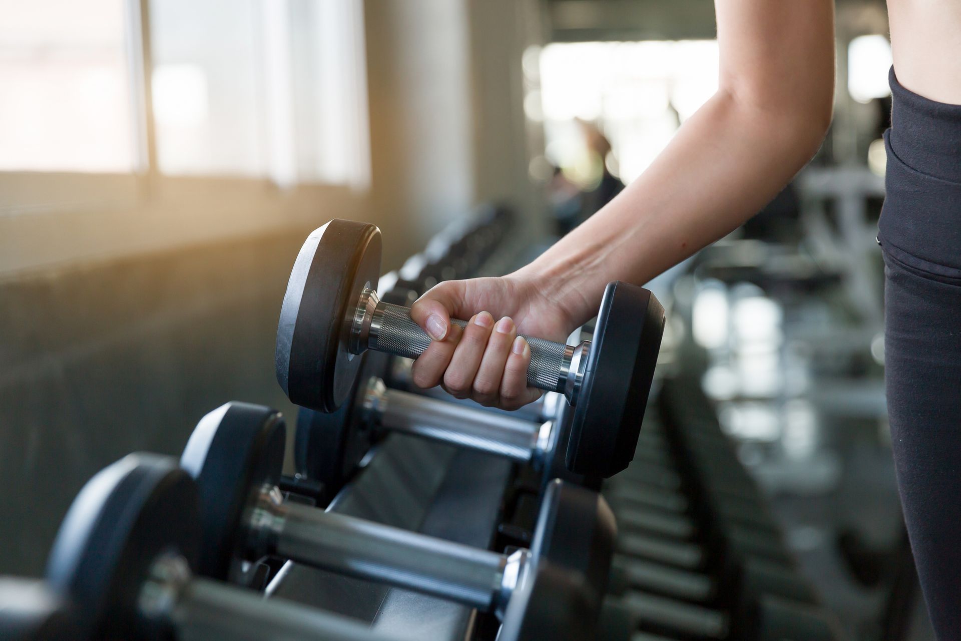 A woman is holding a dumbbell in her hand in a gym.