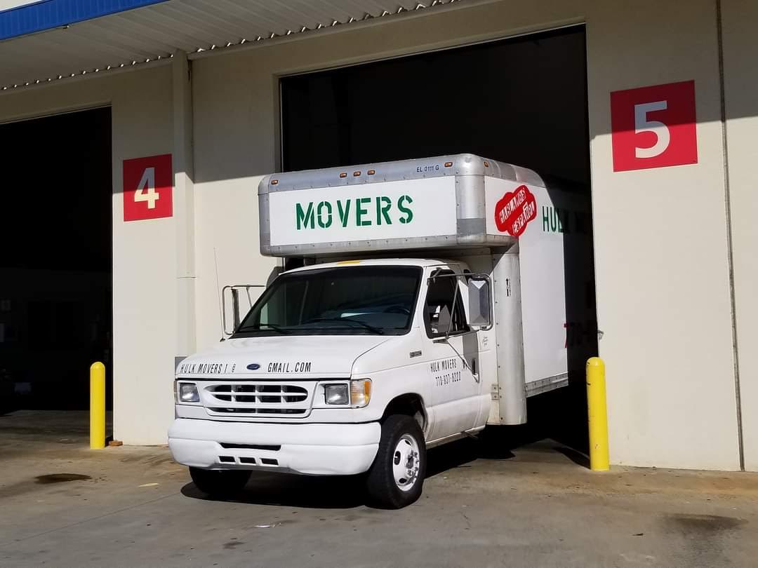 A white movers truck is parked in front of a building