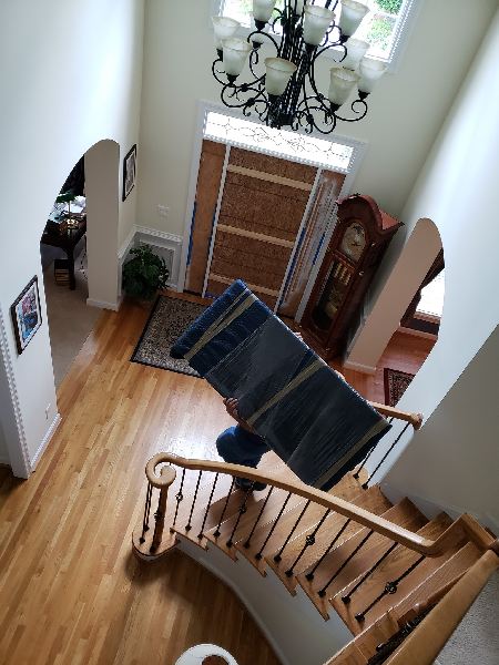 A man is carrying a blanket up a set of stairs.