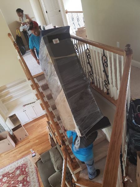 A man is carrying a large box up a set of stairs.