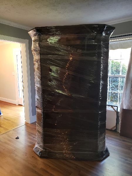 A pillar is wrapped in plastic wrap in a living room.