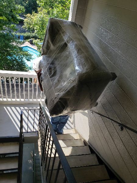 A man is carrying a large piece of furniture up a set of stairs.