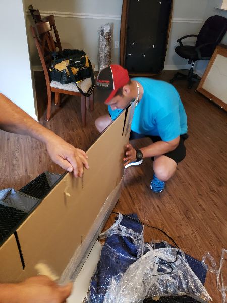 A man in a blue shirt and red hat is kneeling down and working on a piece of cardboard