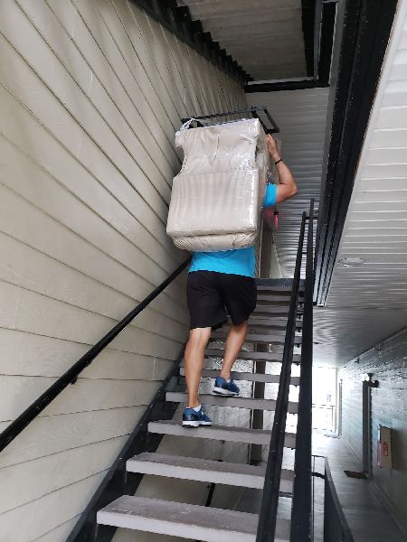 A man is carrying a large box up a set of stairs.