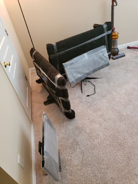A vacuum cleaner is sitting on the floor next to a couch.