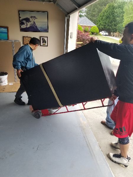 A man and a woman are carrying a large black box