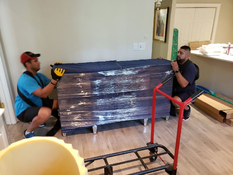 Two men are moving a large piece of furniture in a living room.