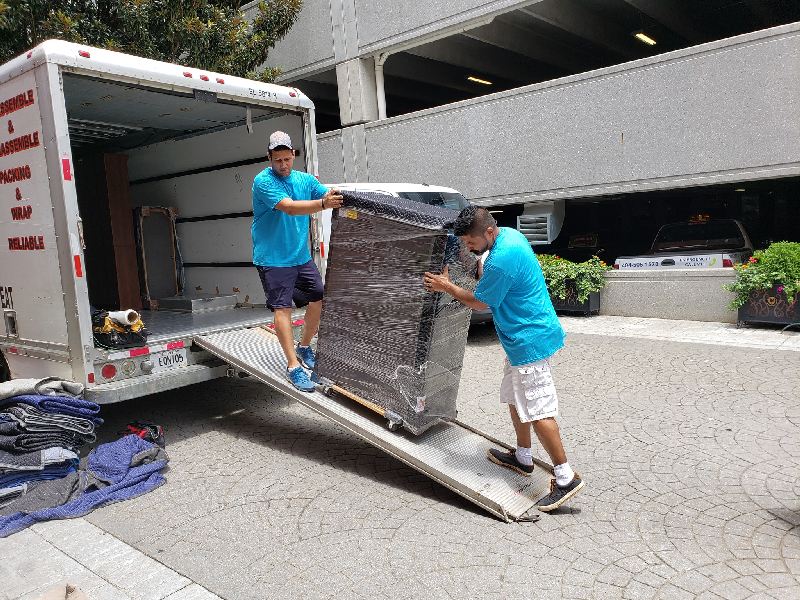 Two men are loading a refrigerator into a moving truck.