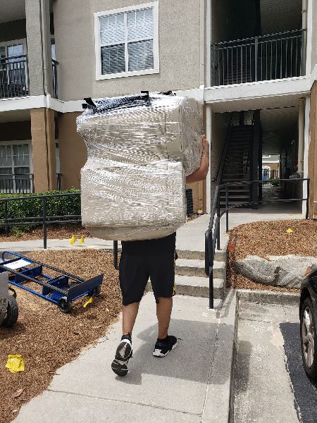 A man is carrying a large piece of furniture on his back.