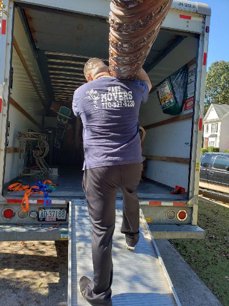 A man is carrying a large piece of furniture into a moving truck.
