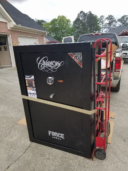 A large black safe is sitting on top of a red dolly.