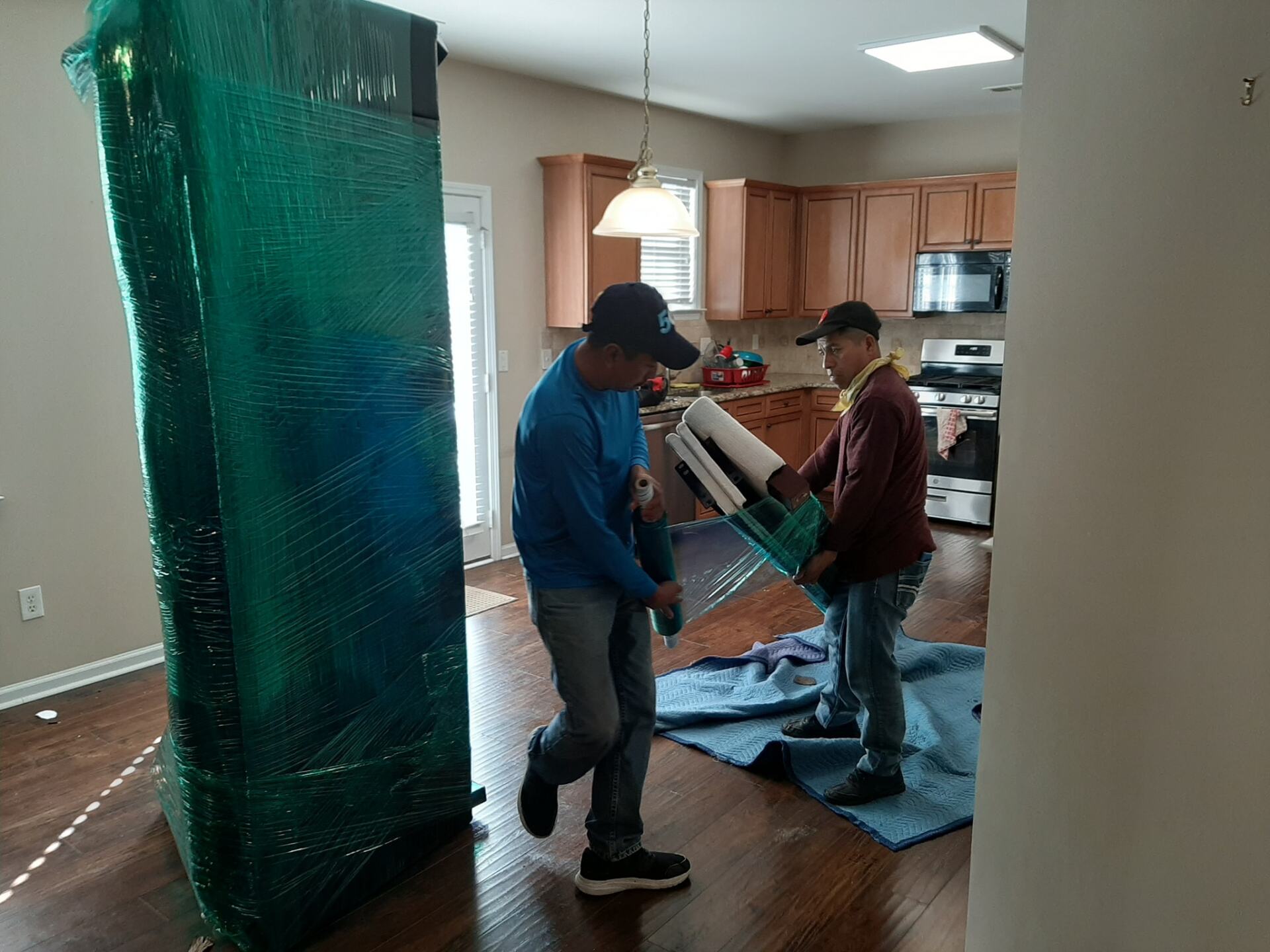 Two men are moving a refrigerator in a kitchen.