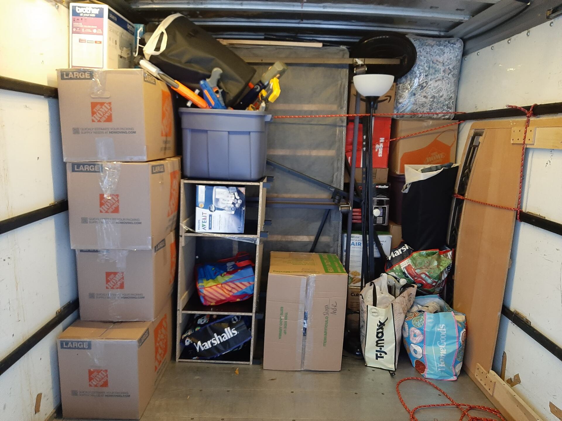 The inside of a moving truck filled with boxes and a bag that says work