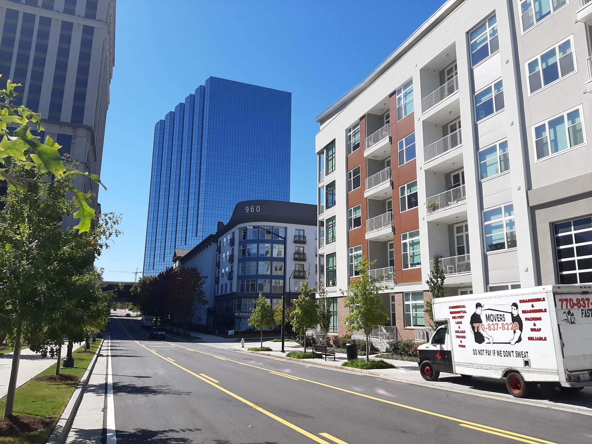 A moving truck is parked on the side of the road in front of a building.