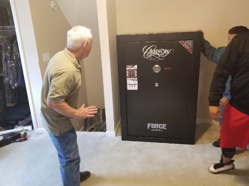 A man is standing next to a large safe in a room.