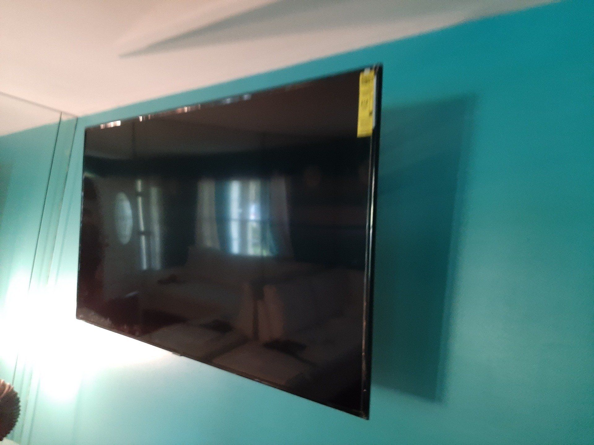 A flat screen tv is mounted on a blue wall