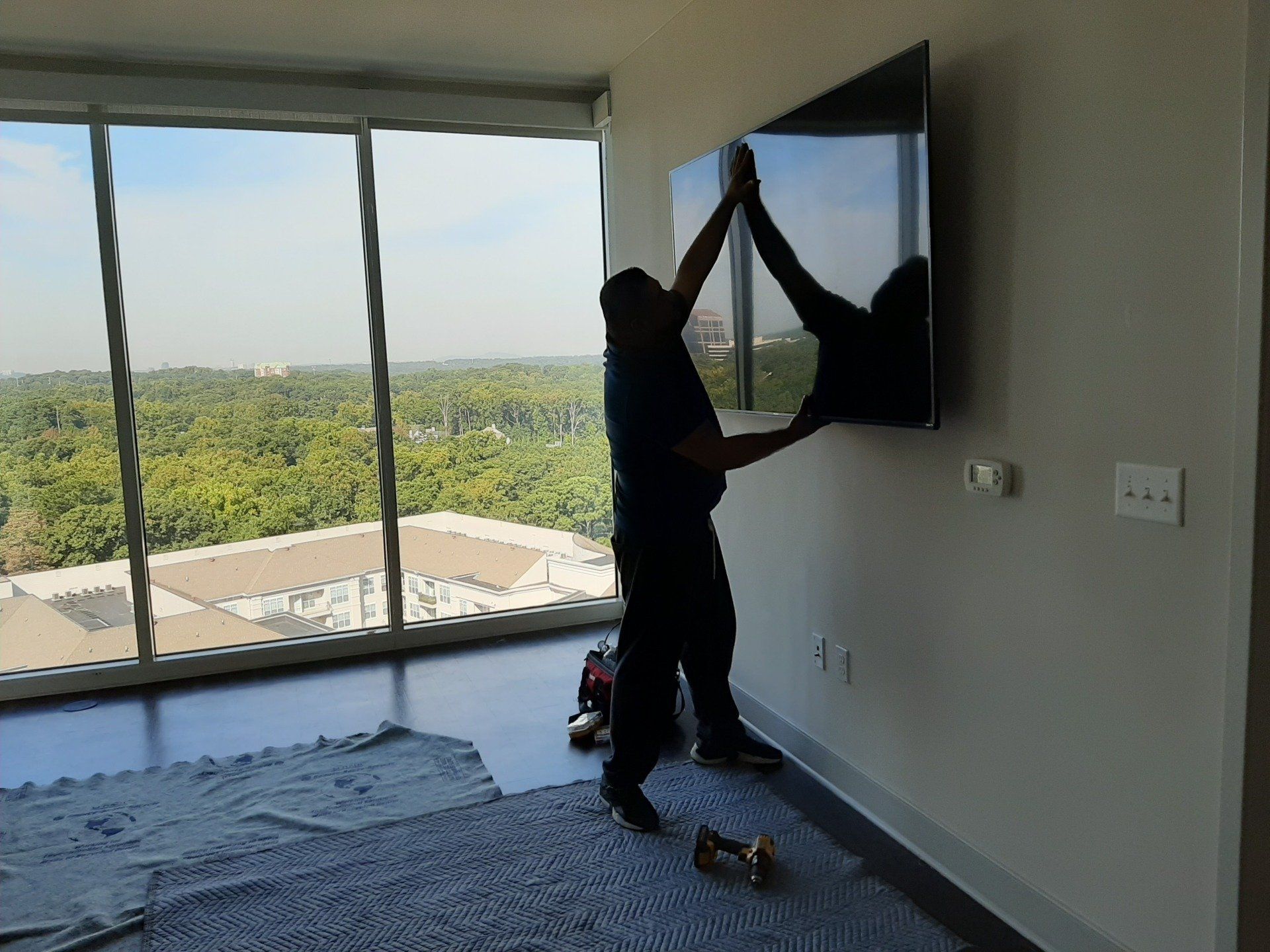 A man is hanging a flat screen tv on a wall.