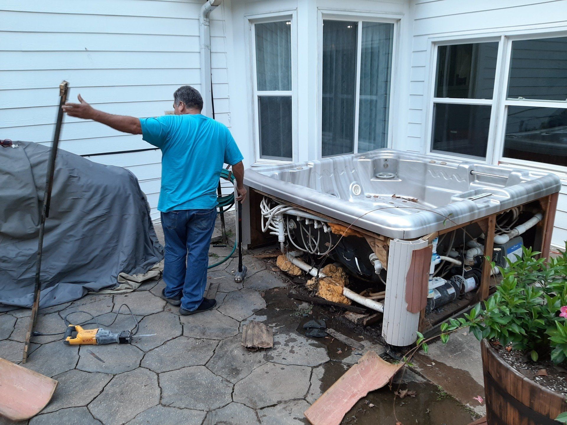 A man is working on a hot tub outside of a house.