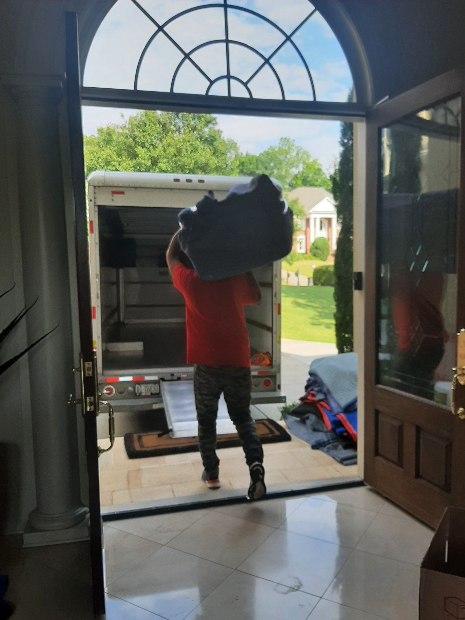 A man is carrying a large piece of furniture into a truck