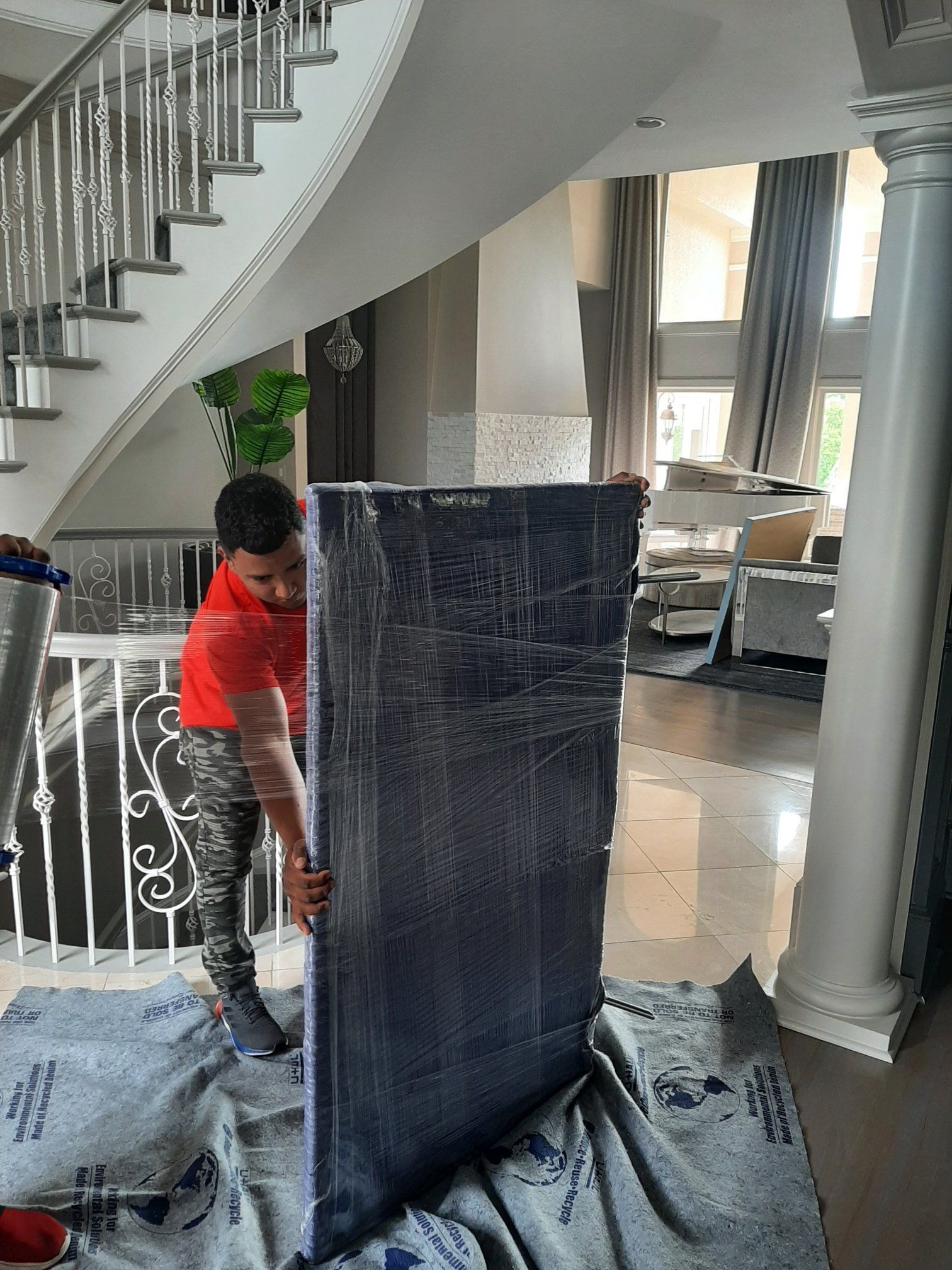 A man is holding a large piece of furniture in a living room.