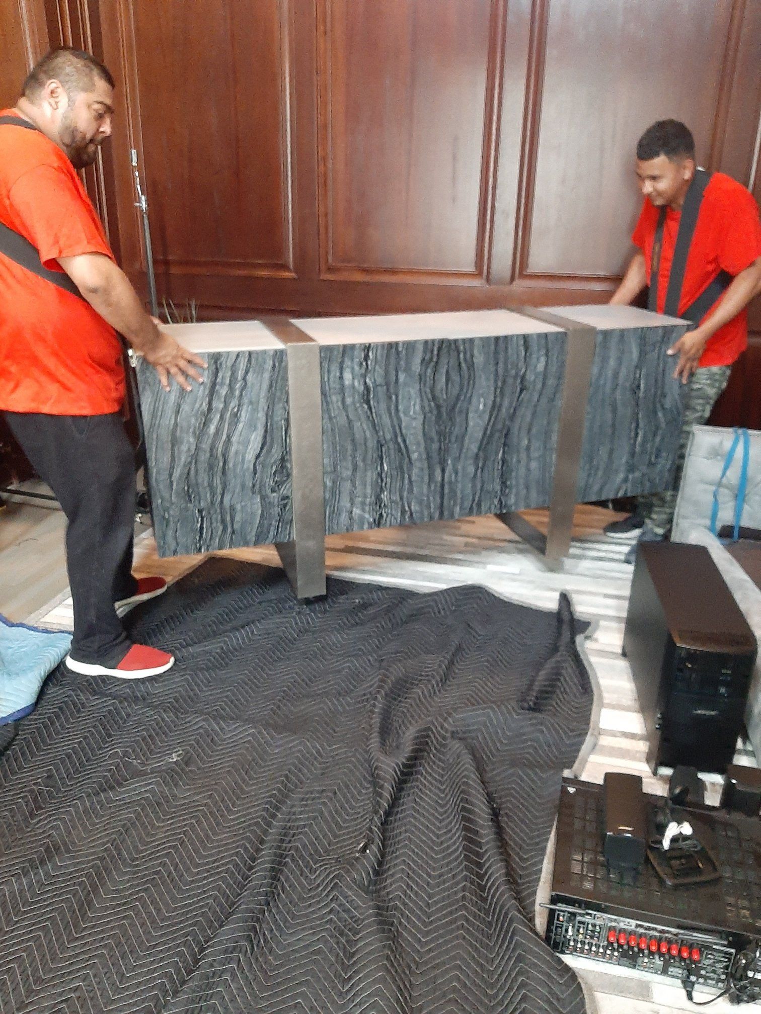 Two men are moving a table in a room.
